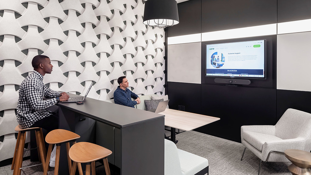 Men sitting at a table with a laptop and a projector screen.