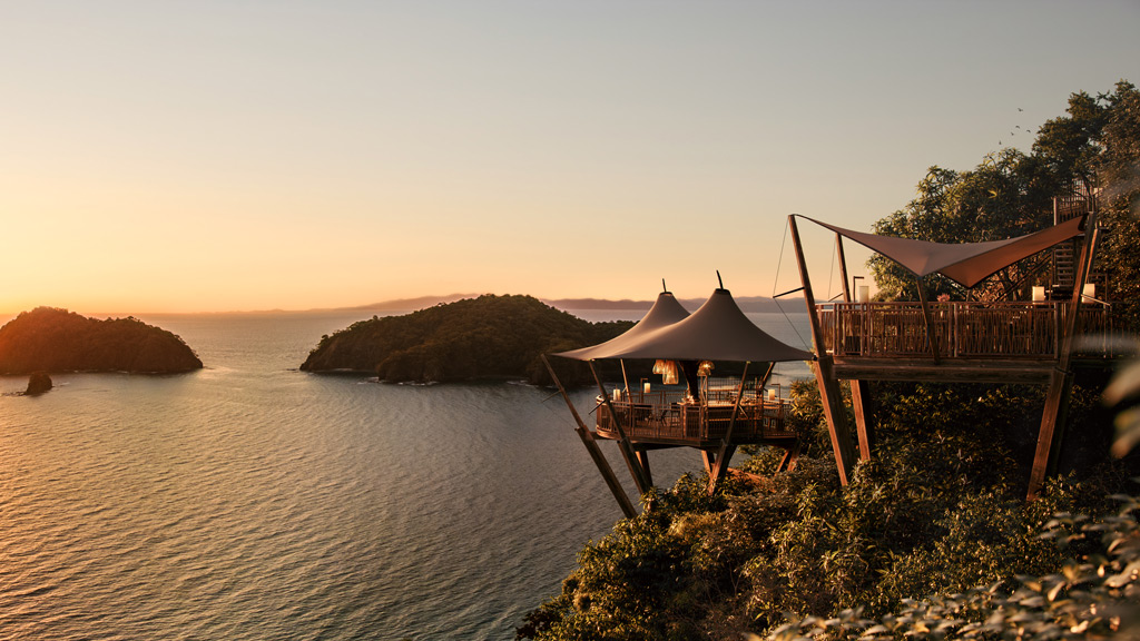 A table and chairs on a cliff above water.