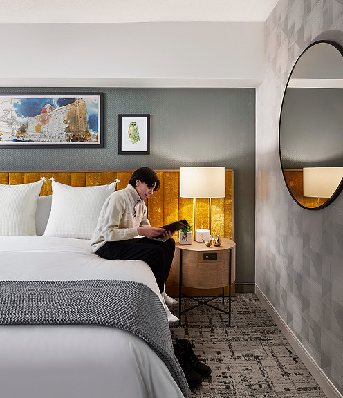 A person sitting on a bed reading a book in a boutique hotel room at Voco Holiday Inn