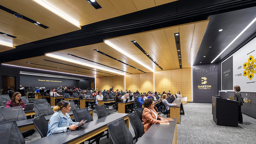 A person giving a presentation to a group of people in an auditorium at Wichita State University Business School
