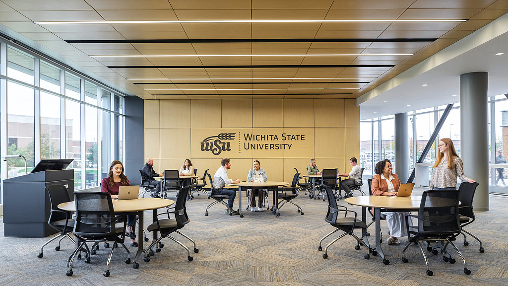 A group of people sitting at tables in an airy classroom at Wichita State University Business School