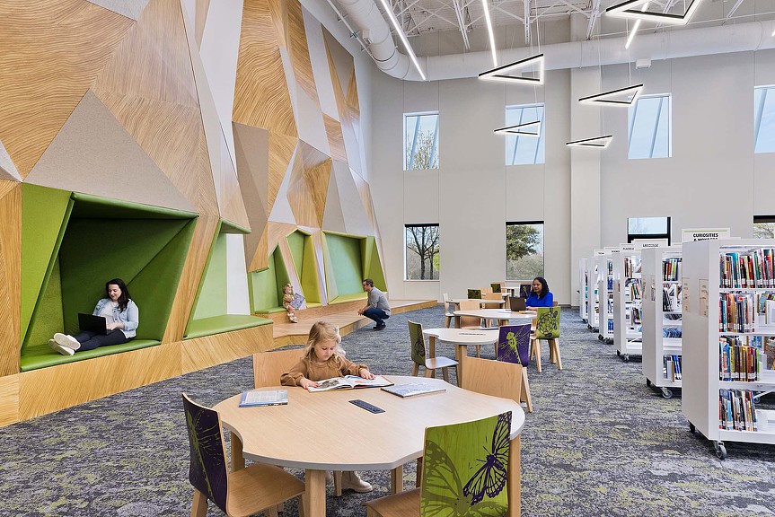 A group of people sitting at tables in a library.