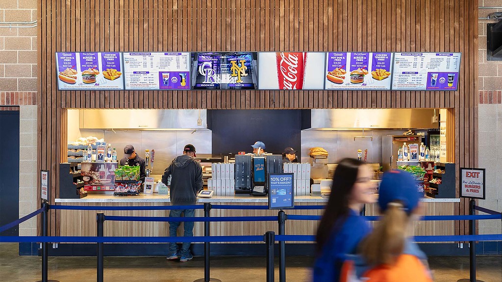 A group of people standing in front of a counter with food on it.