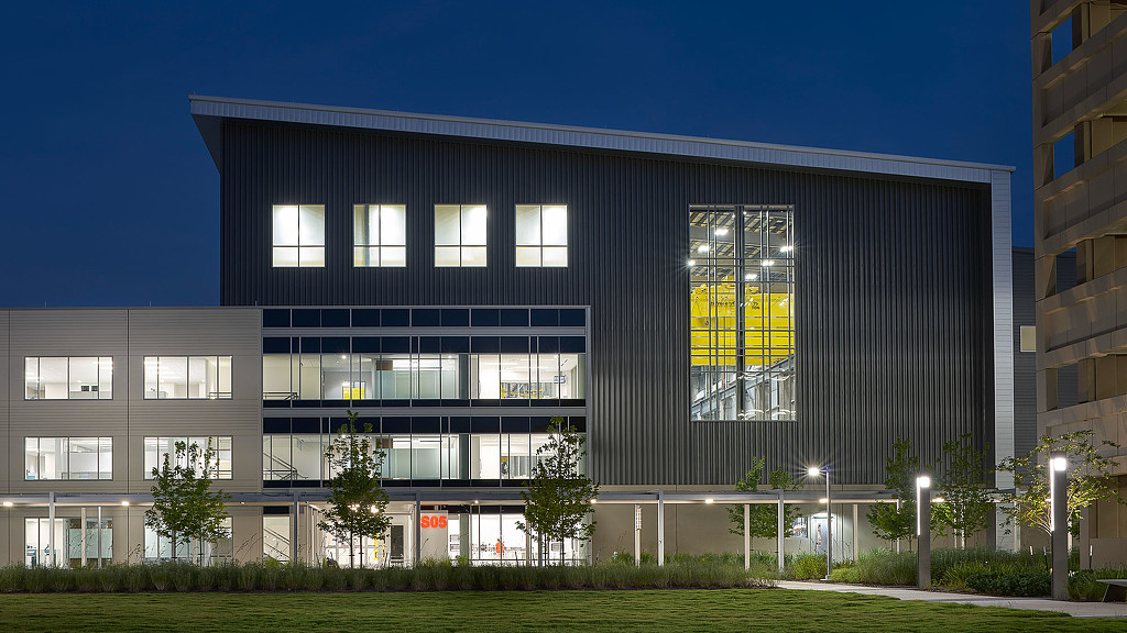A building with windows and grass in front of it.