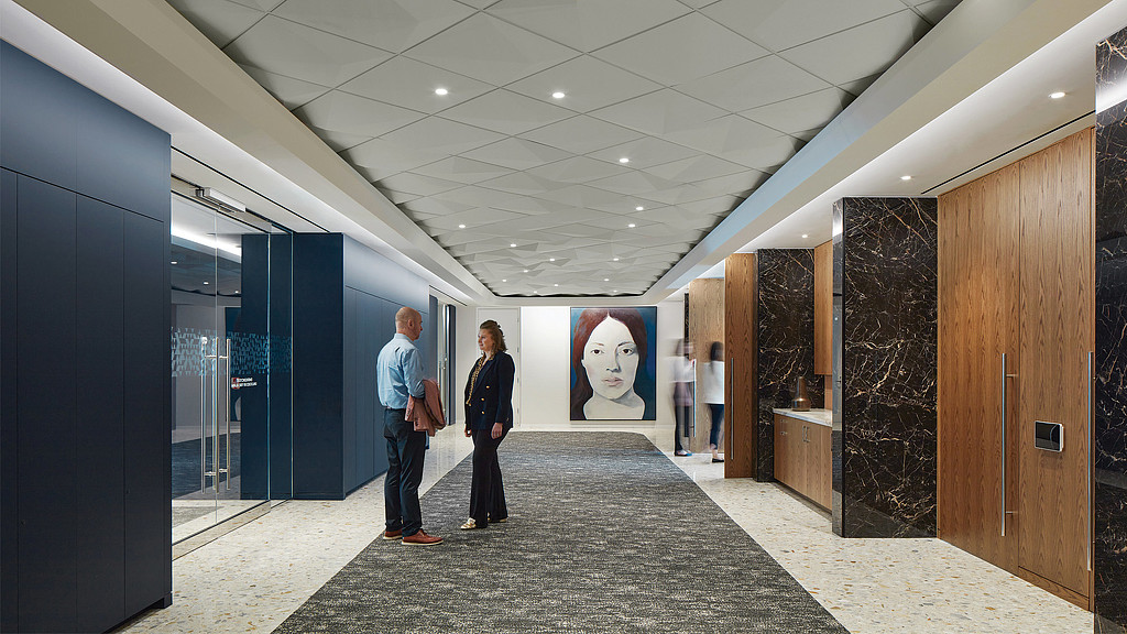 A man and a woman standing in a hallway with a large poster on the wall.