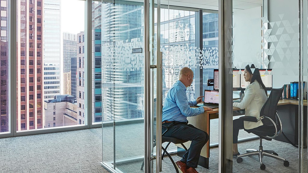 A man and woman sitting at a desk in an office.