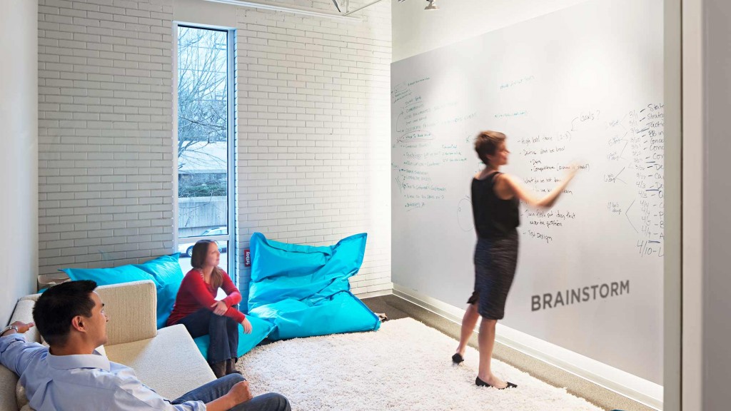 A man standing in front of a whiteboard in a room with people.