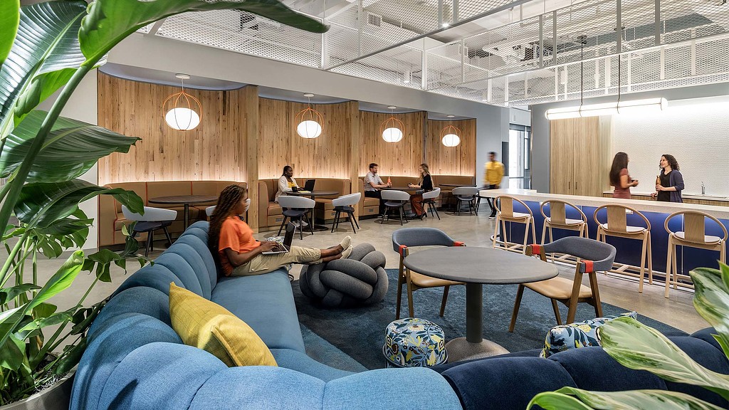 A group of people sitting in a room with tables and chairs.