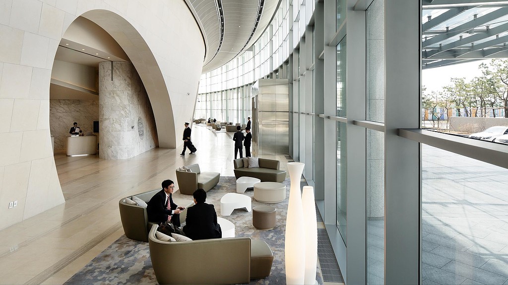A group of people sitting on white couches in a building.