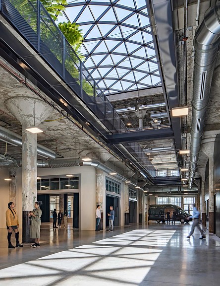 A group of people walking inside a building with a large skylight window on the ceiling