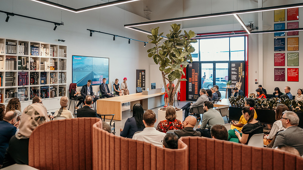 A group of people sitting in a room with a large screen.