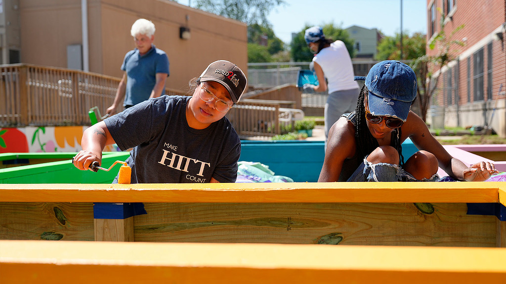 Team members painting Roots to Success planter boxes