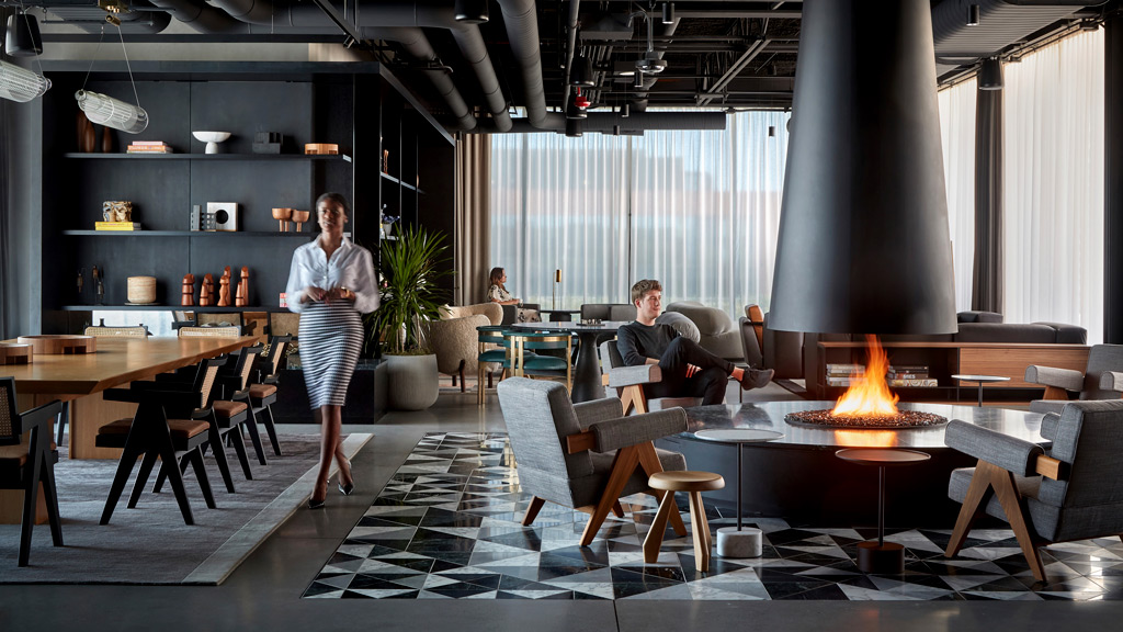 A person standing in a room with tables and chairs.