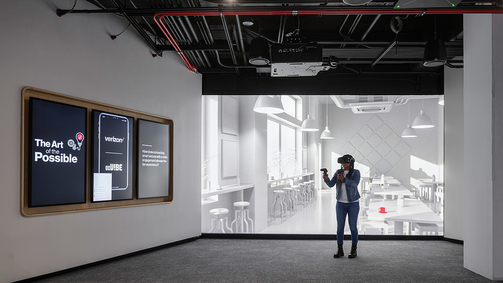 A woman standing in the Verizon Innovation Center, San Francisco with a VR set