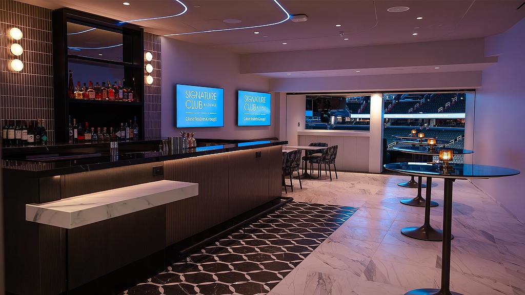 A bar with a tv and a table with drinks on it.