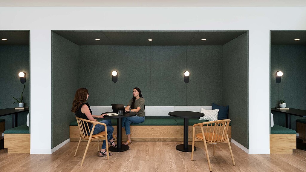 A couple of women sitting at a table with laptops.