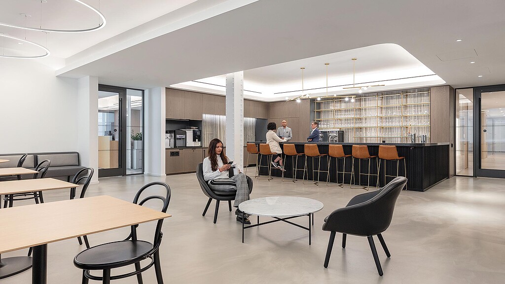 A group of people sitting at tables in a room with a large window.