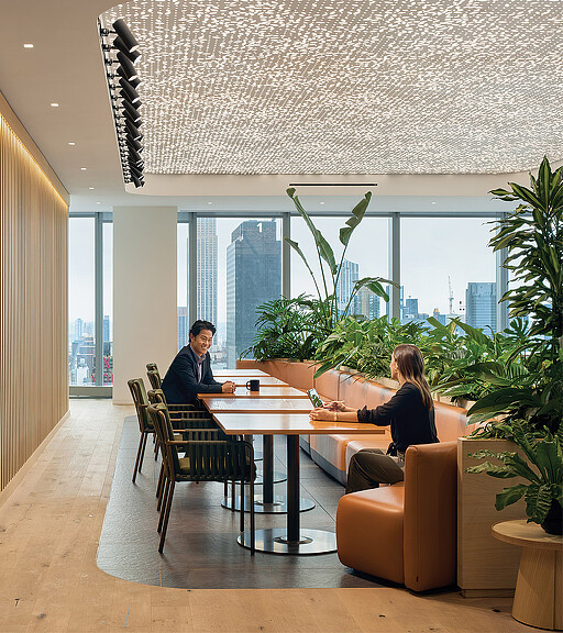 A man and woman sitting at a table in a room with a large window.