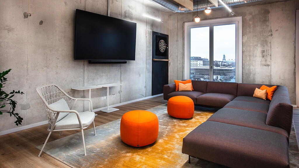 KAYAK Booking Holdings Berlin office interiors with couches and screen