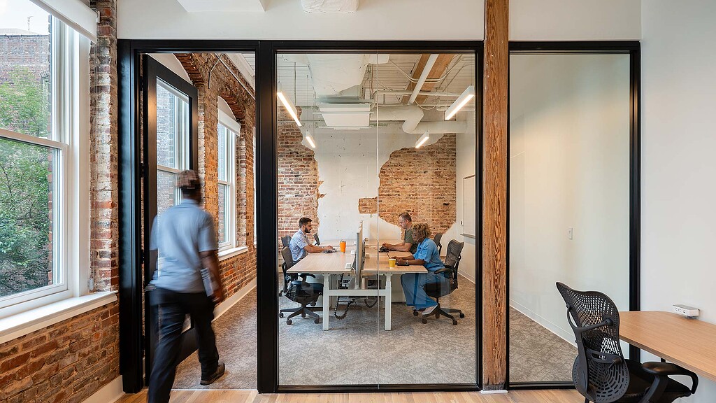 A person standing in a room with a table and chairs.