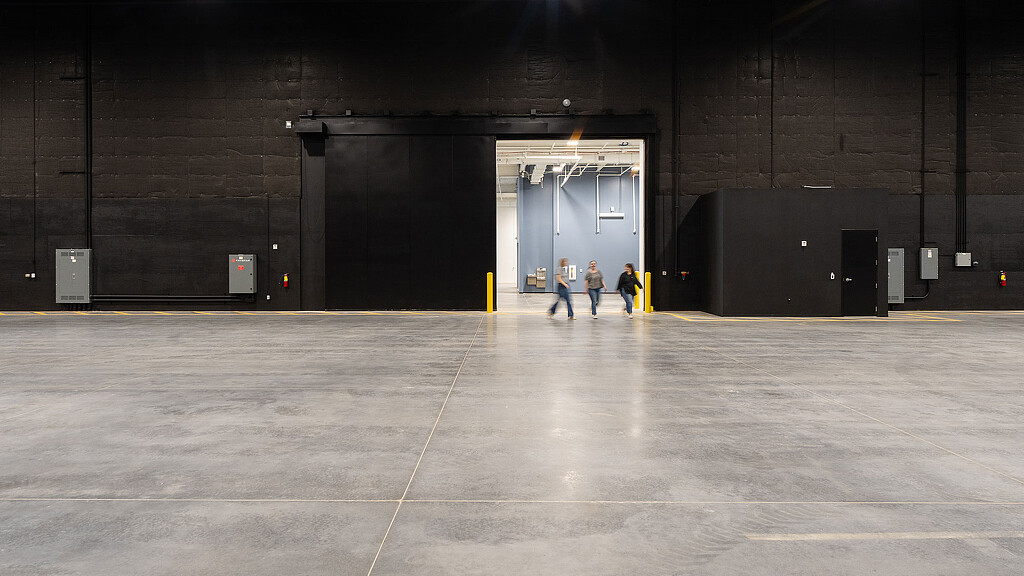 A group of people walking in a large empty room.