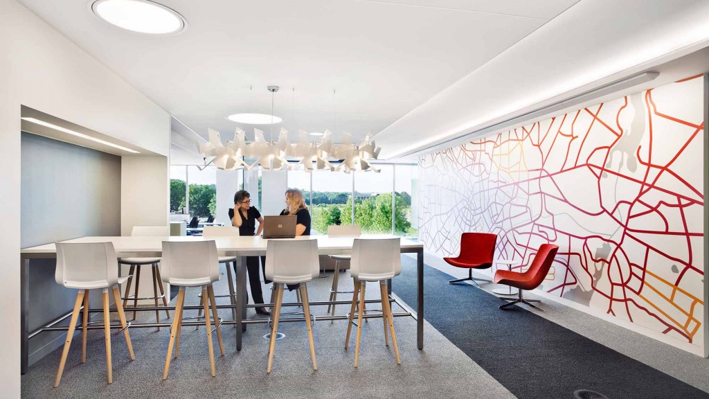 A couple of people sitting at a table with chairs and a red and white wall with a red.