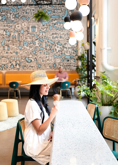 Woman with hat eating ice cream inside Cosmic Bliss