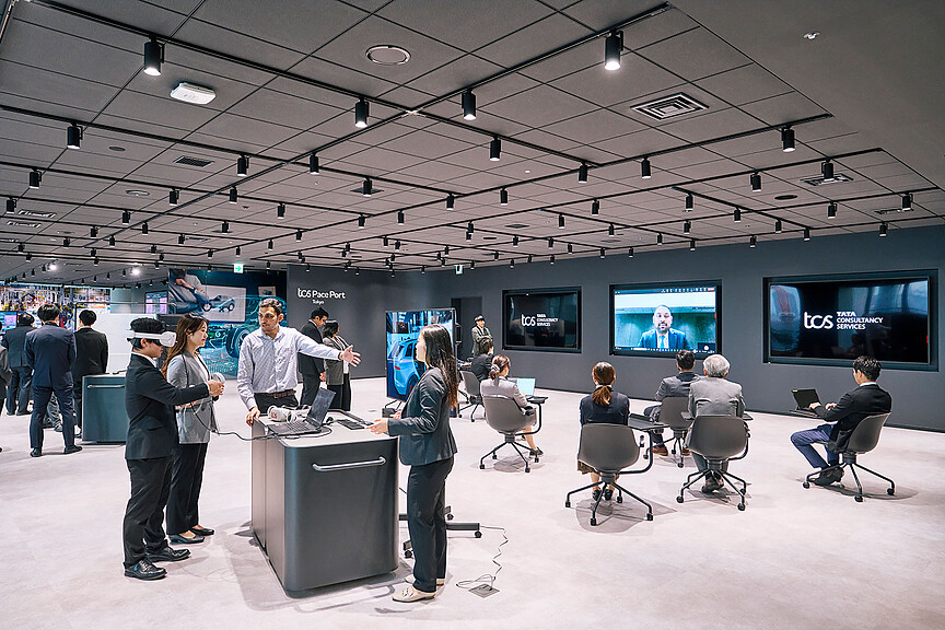 A group of people in a room with large screens.
