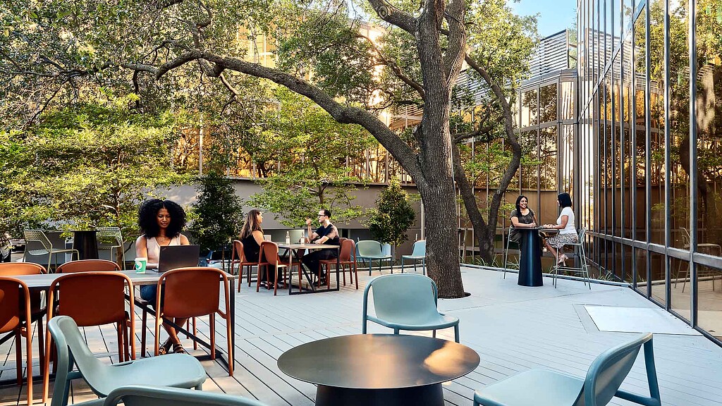A group of people sitting at tables outside.