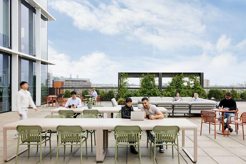 A group of people sitting at tables outside.