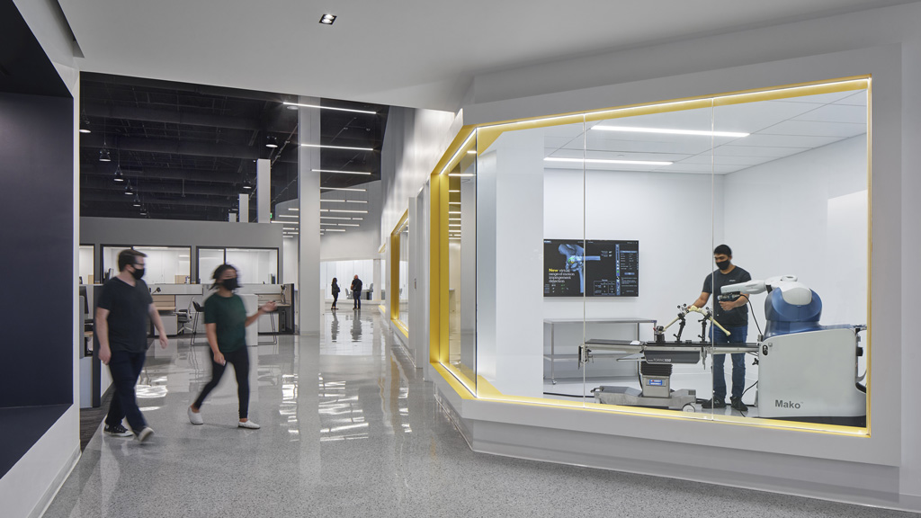 People in a room with a glass wall and a white floor.