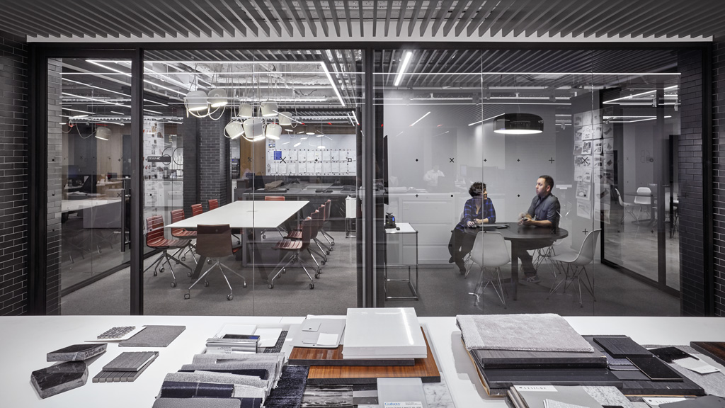 A couple of people sitting at a table in a room with a large glass wall and a large.