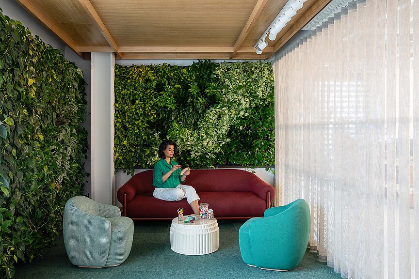 A person sitting on a couch in an Etsy Dublin space with plant walls
