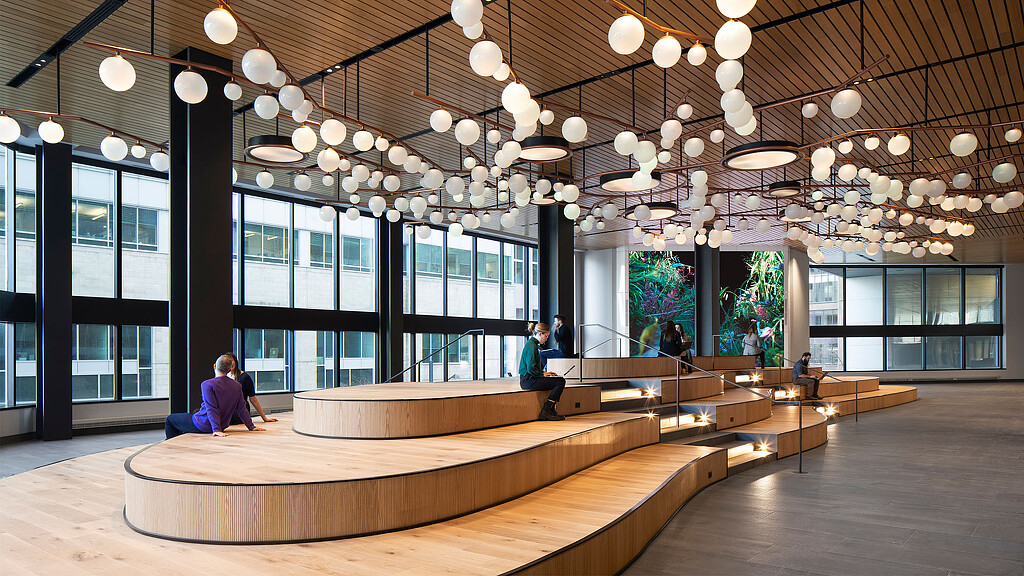 A couple of people sitting at a table in a large room with large windows and chandeliers.