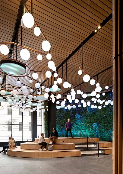 A group of people sitting on a bench under a chandelier.
