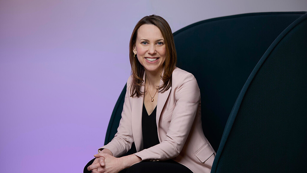 A woman sitting in front of a blue wall.