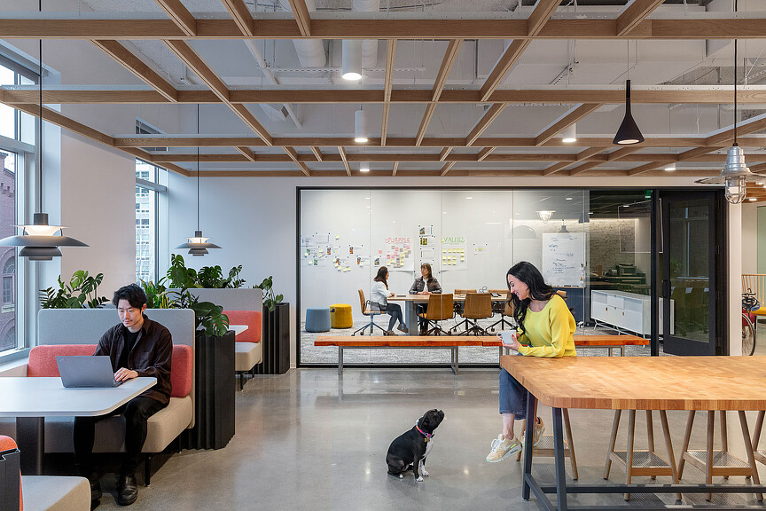 A dog and a person in a room with tables and people.