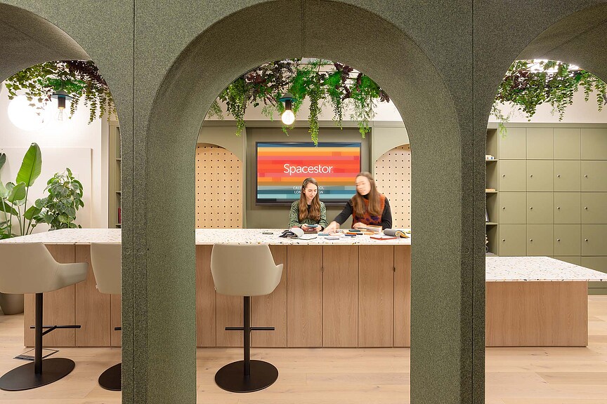 A couple of women sitting at a table in a room with plants.