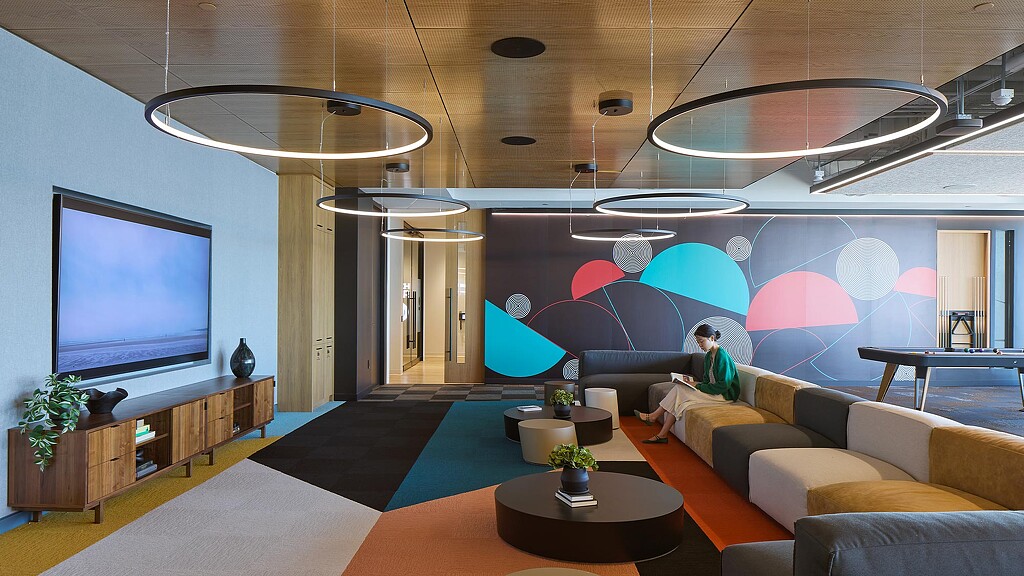 A person sitting on a couch in a room with a large screen.