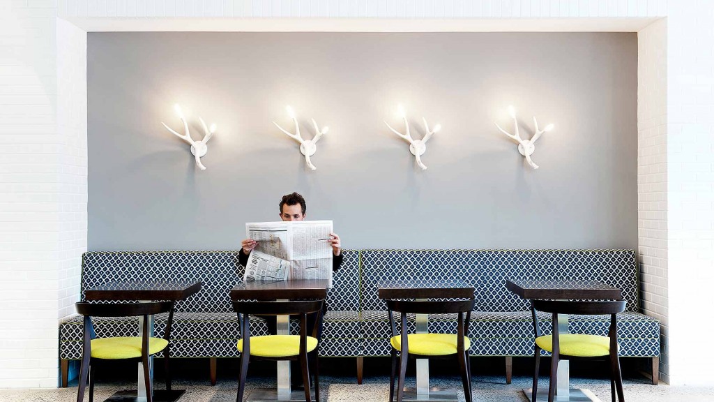 A person sitting at a table with a laptop and several chairs.