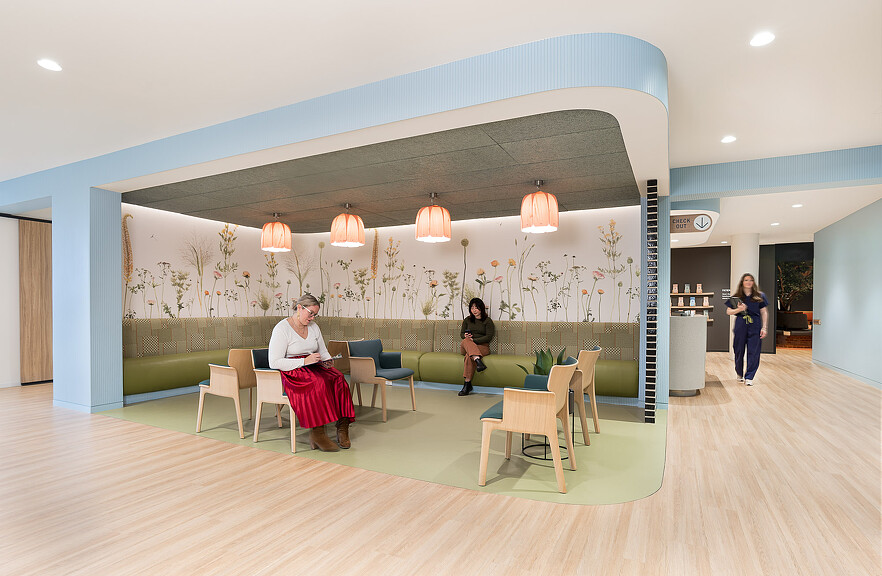 A man and woman sitting in a room with a large painting on the wall.