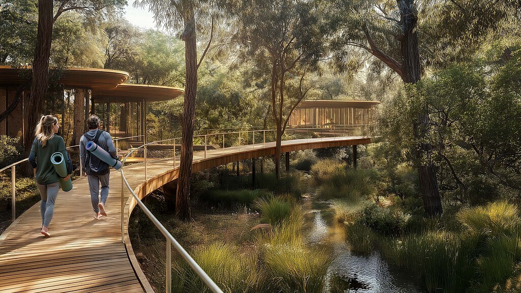 A couple of people walking on a wooden bridge over a stream.