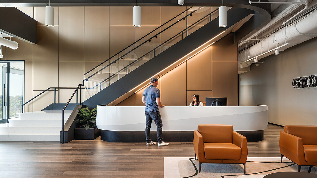 A person standing in a room with a staircase and chairs.