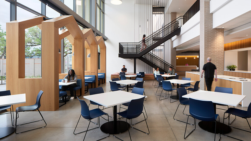 A group of people sitting at tables in a room with windows.