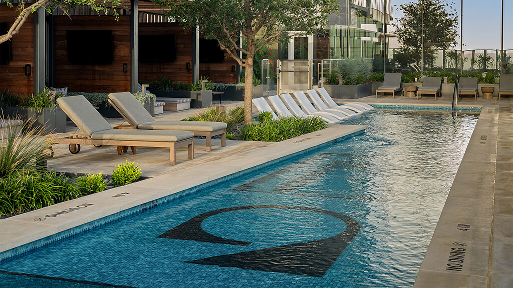A swimming pool with benches and a building in the background.