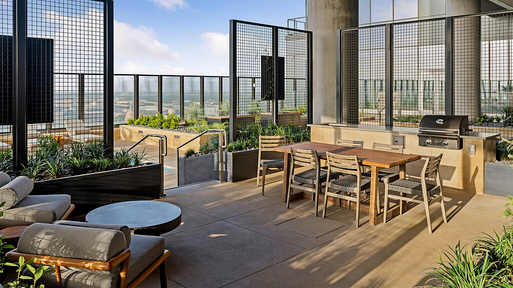 A patio with tables and chairs and a grill on it.