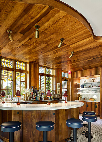 A kitchen with stools and a bar.