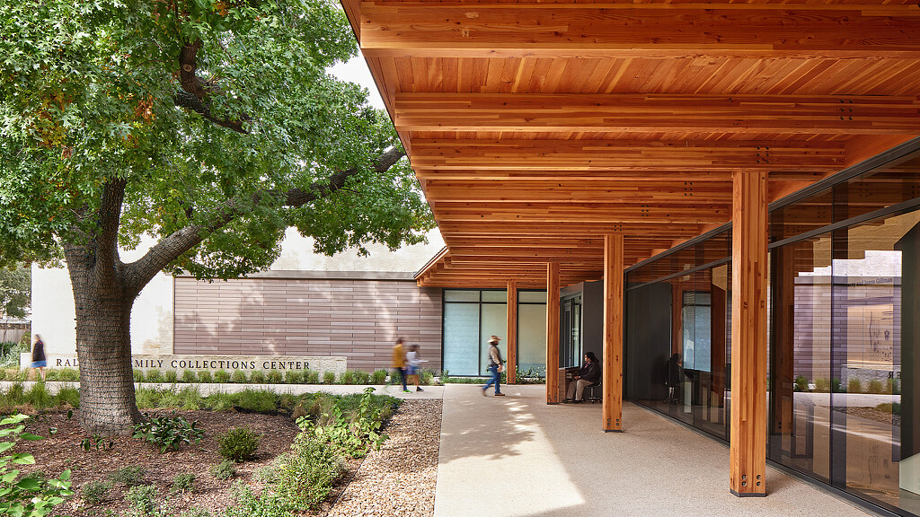 A building with a tree and people walking around.
