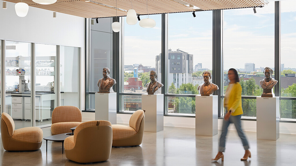 A person walking in a room with a large window and statues.