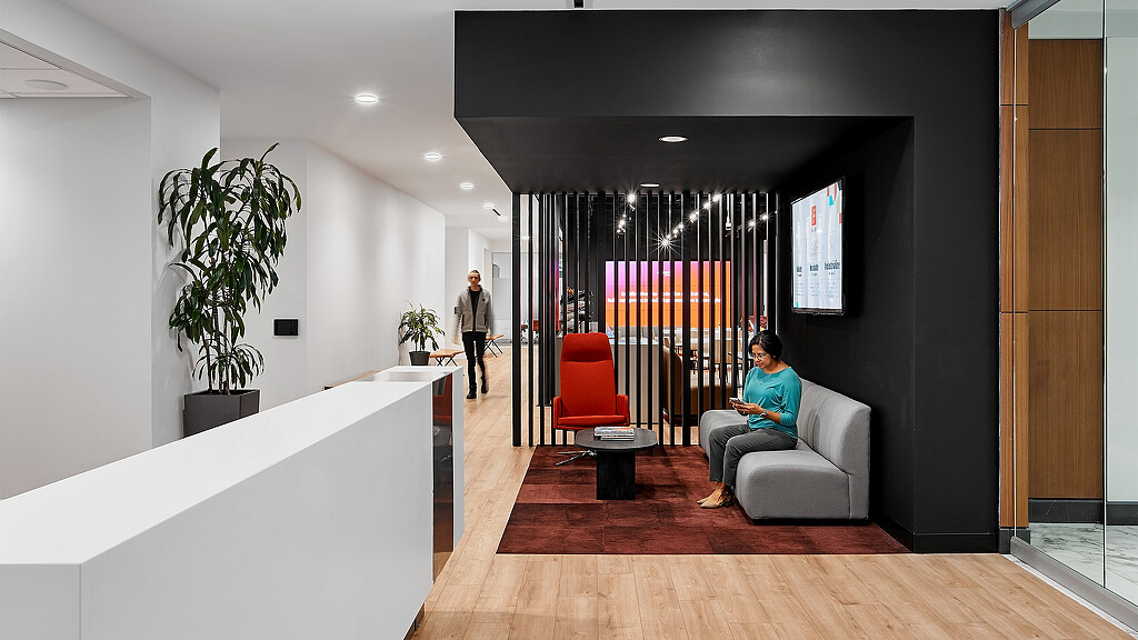 A man sitting on a couch in a room with a woman standing.